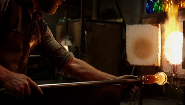 AI-generated frame: a glassblower shaping glowing glass at a furnace