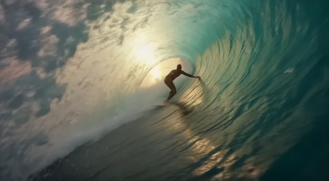 AI-generated frame: a surfer inside a barrel wave at sunrise